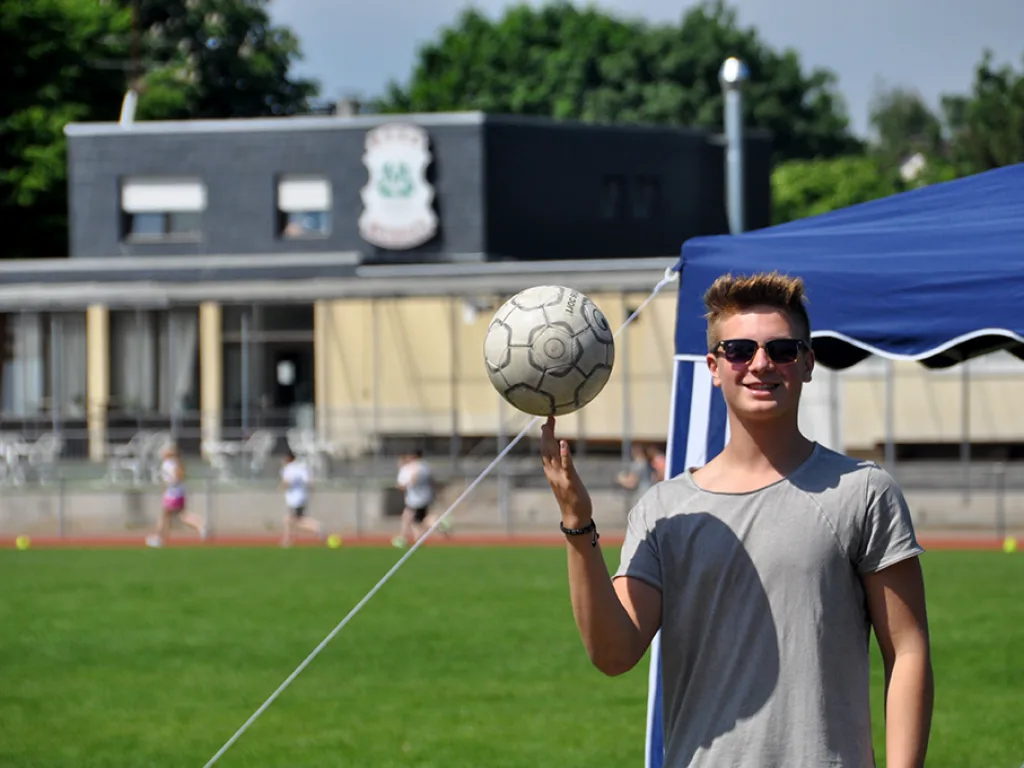 Jugendlicher balanciert einen Fußball auf dem Finger.